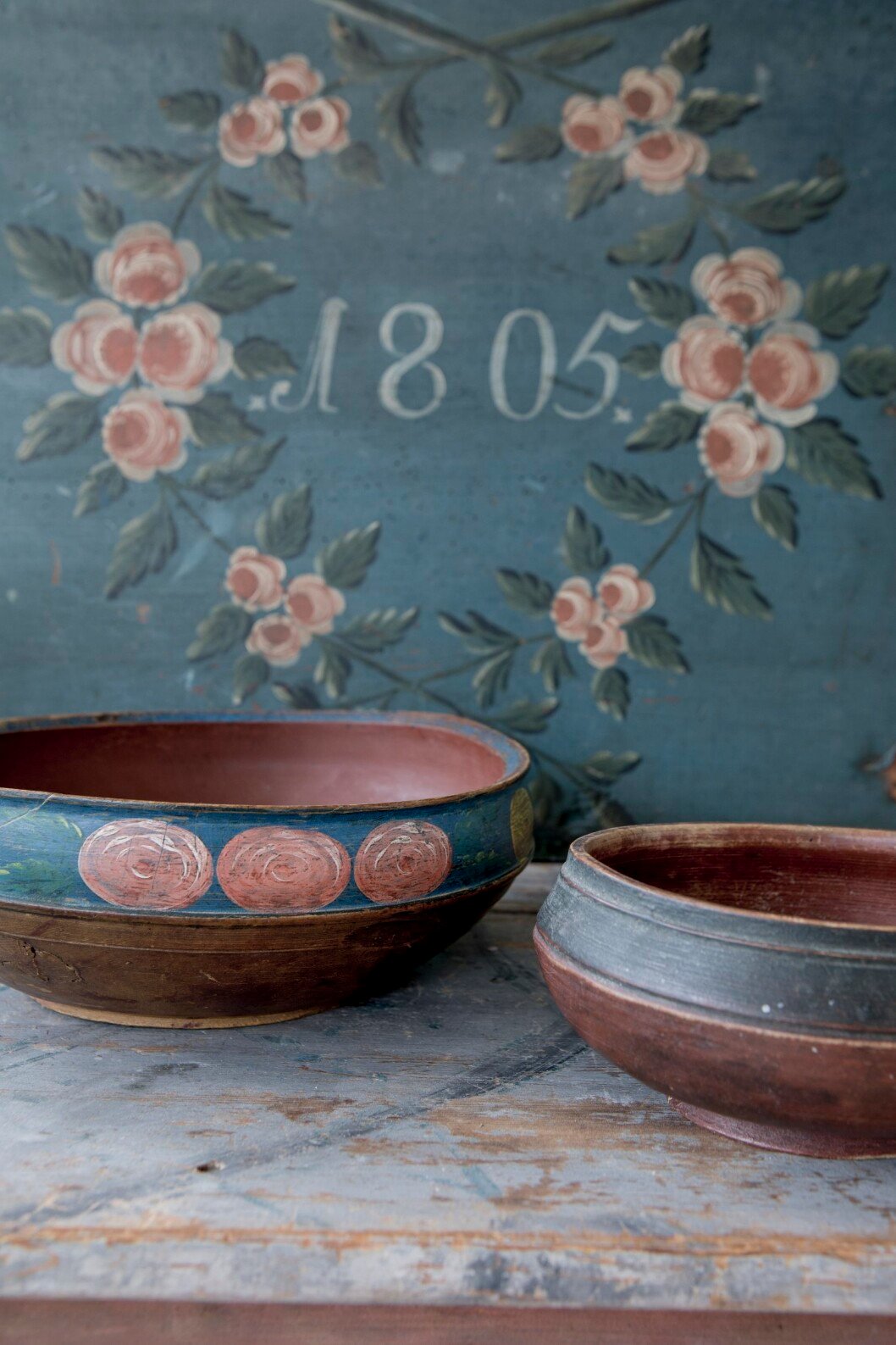 Fin färgsättning har den bohuslänska så kallade ölbollen med blomstermotiv från 1800-talets första hälft. Priset sattes till 5 000 kronor hos Brobackens Antik. Ölbollen är en typ av målat dryckeskärl som svarvats till en rund form. Två träskålar i allmoge, blå och rosa allmogedekor i bakgrunden.