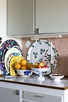 Vackra brickor på rad i köket, från bland annat Svenskt Tenn. Porslinet är bland annat Musselmalet från Royal Copenhagen.