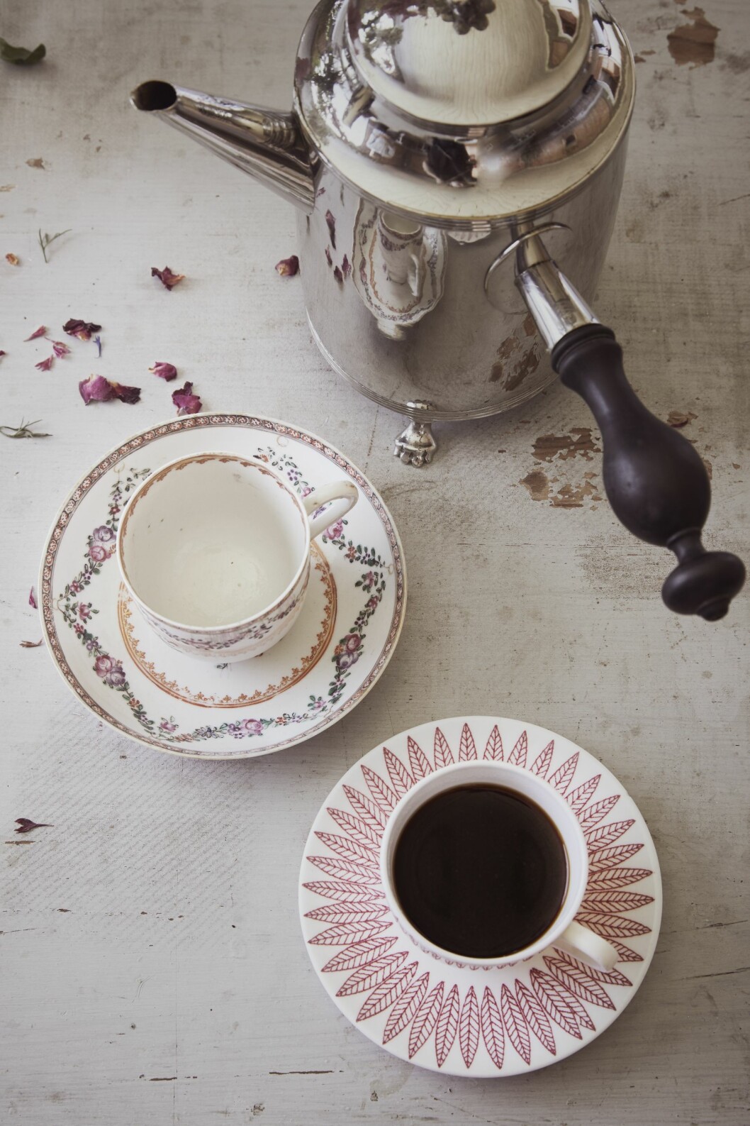 Den eleganta kaffekoppen med vad som brukar kallas europeiserande mönster är tillverkad i Kina under senare delen av 1700-talet för export till Europa. Prislappen visar 1 000 kr hos Le Village Antik. Den andra koppen, som i princip har samma form som 1700-talsmodellen, ingår i servisen Salix och är ritad av Stig Lindberg (1916–82) under 1950-talet för Gustavsberg. Le Village antik begär 100 kr. Två mönstrade med fat syns uppifrån tillsammans med en kaffekanna i metall och trähandtag.