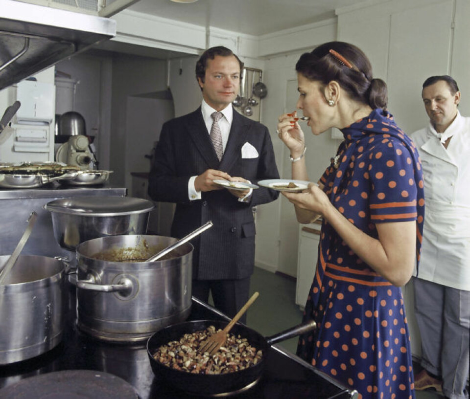 Silvia 1980. Det var vid en provsmakning med fotografering i köket på Stockholms slott som drottningen bar den blå klänningen med korallrosa prickar, knyt i halsen och kort ärm. Matchande kammar i det mörka håret fullbordade looken. Silvia 1980. Det var vid en provsmakning med fotografering i köket på Stockholms slott som drottningen bar den blå klänningen med korallrosa prickar, knyt i halsen och kort ärm. Matchande kammar i det mörka håret fullbordade looken.
