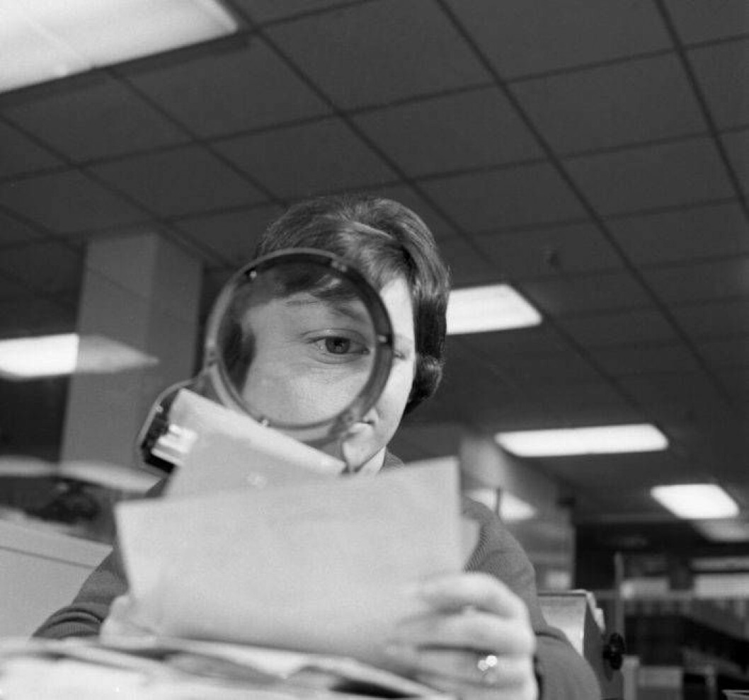 En kvinna tittar på några papper genom ett förstoringsglas.