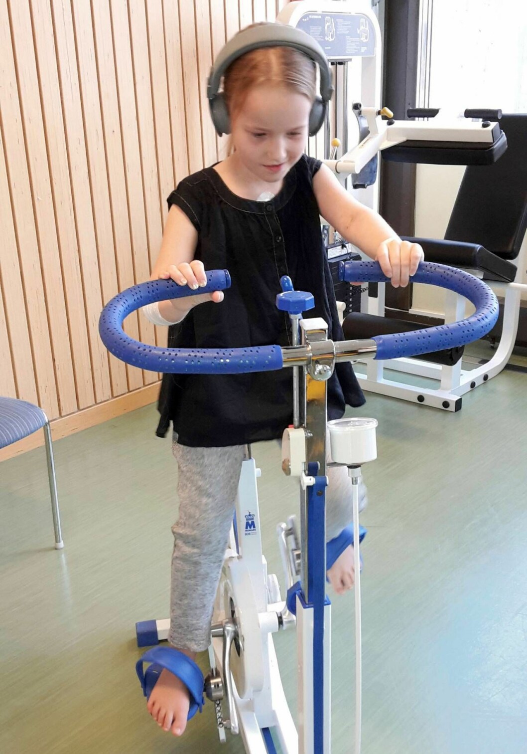 Vilma tränar på en cykel i sjukhusmiljö 