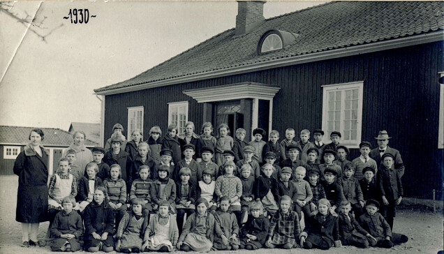 Ett gammalt skolfoto från1930. Flickorna bär förkläden och pojkarna kepsar i samma modell som eleverna nu har återskapat. Skolan var mycket modern i sin arkitektur med det utsvängda taket. Ett gammalt skolfoto från1930. Flickorna bär förkläden och pojkarna kepsar i samma modell som eleverna nu har återskapat. Skolan var mycket modern i sin arkitektur med det utsvängda taket.