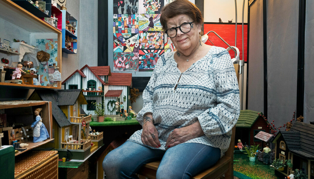 Marianne sitter bredvid sina dockskåp och miniatyrer.