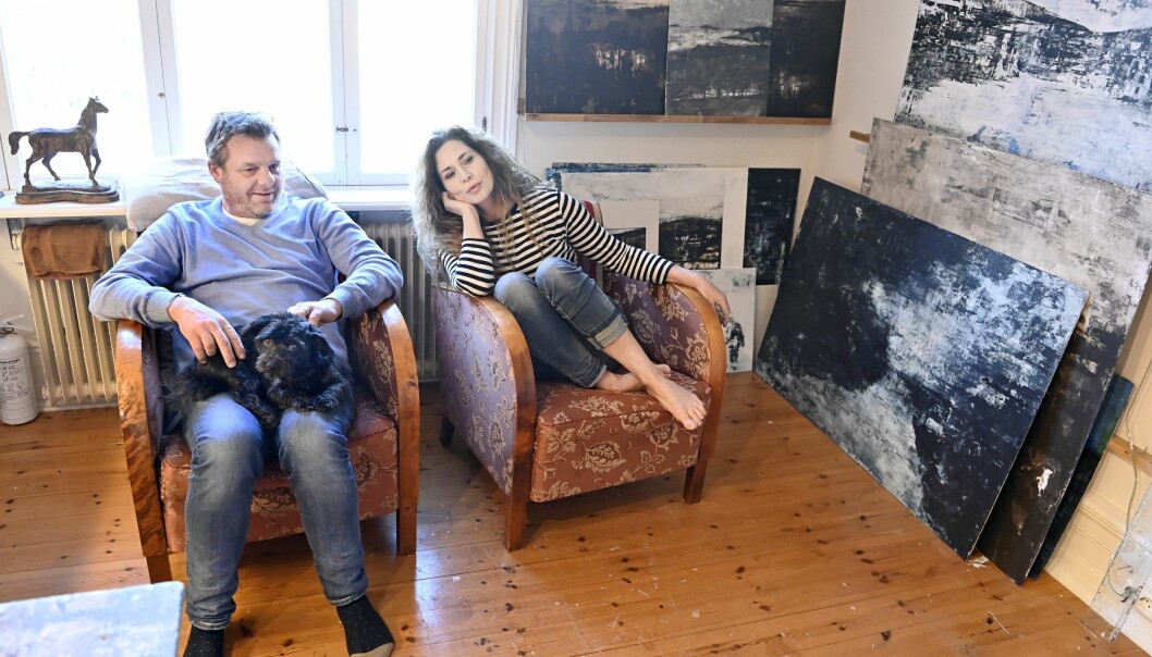 Patrik och Maria Krall med hunden Sigge i ateljén där många av Marias tavlor står uppradade på såväl golv som vägghyllor.