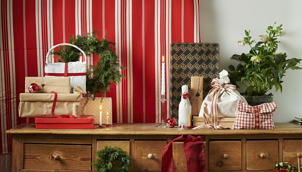 Julklappar på ett träskåp med rödvitrandigt tyg i bakgrunden.