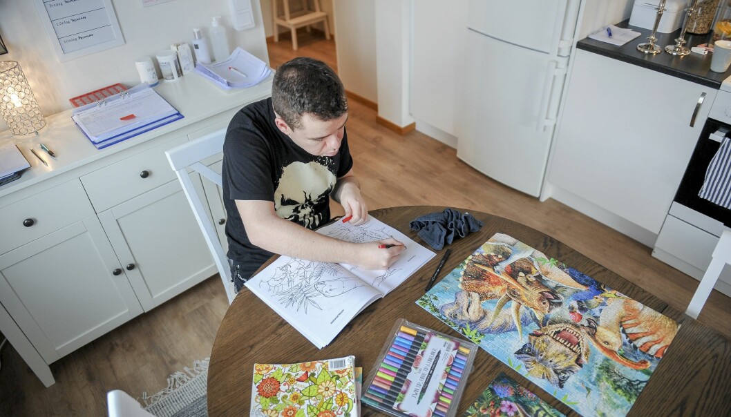 Adam älskar att måla och lägga pussel. Adam sitter vid köksbordet i sitt kök och färglägger dinosaurier i ett målarblock och bredvid honom ligger ett färdiglagt pussel med dinosauriemotiv.