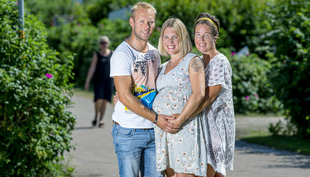 Adam och Sandra står på varsin sida om Linnea och alla ler och håller händerna på Linneas runda gravidmage.
