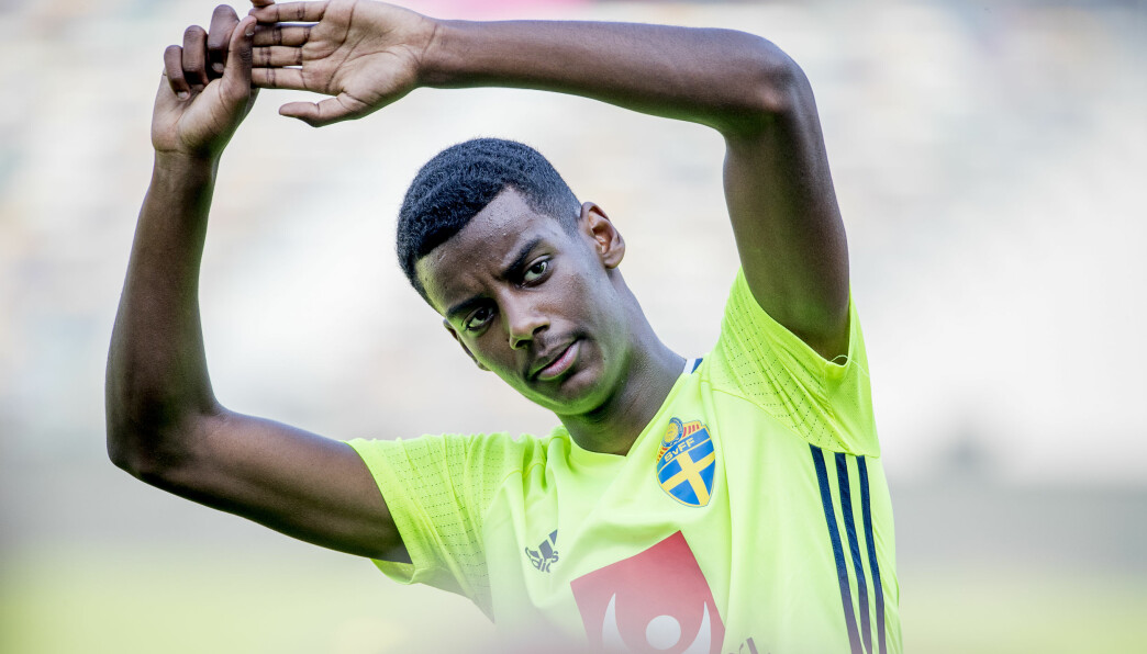 Alexander Isak har en neongul träningströja på sig och sträcker på armarna.