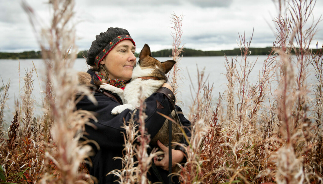 Alexandra kramar om hunden Ronja framför en sjö.