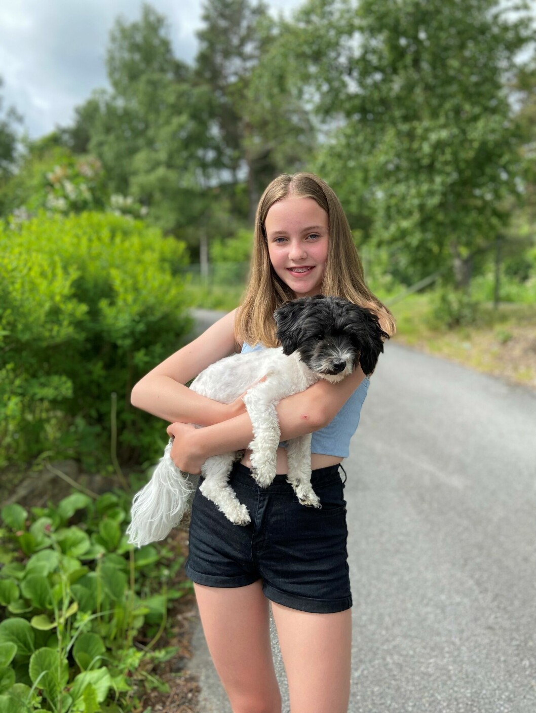 Alice i sommarkläder håller upp sin hund.
