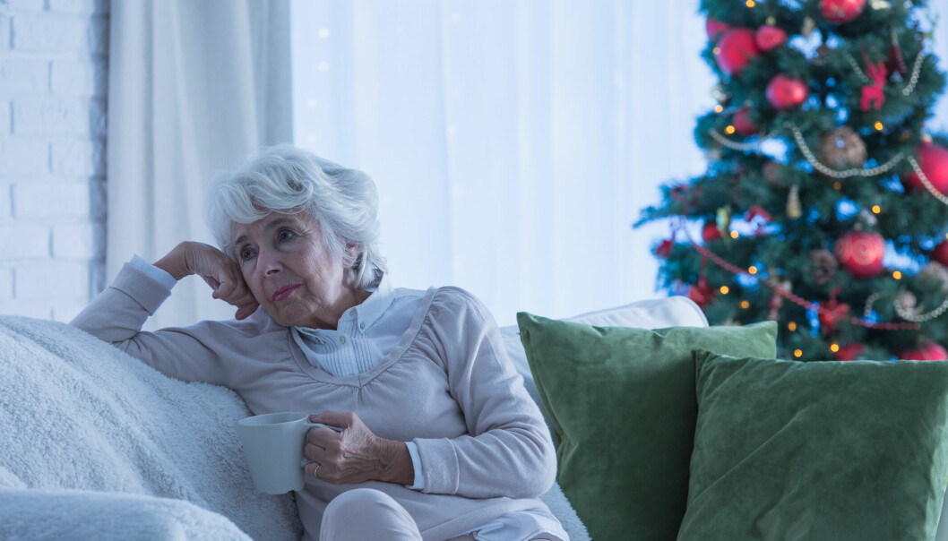 Äldre kvinna ensam vid en julgran