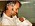 En man i 45-årsåldern ler och håller i sin nyfödde son med en vit liten mössa.