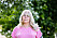 Anette står och tittar in i kameran med rosa tröja och blond långt hår.