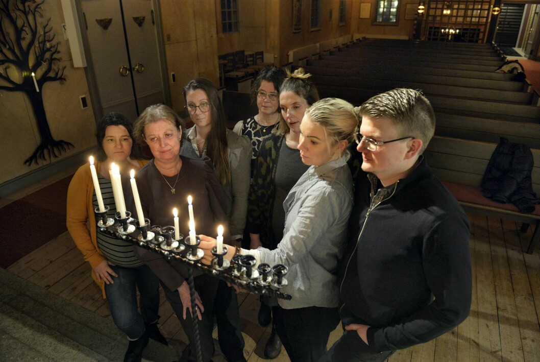 Sju Änglaföräldrar står tätt tillsammans i en kyrka och tänder ljus för sina döda barn.