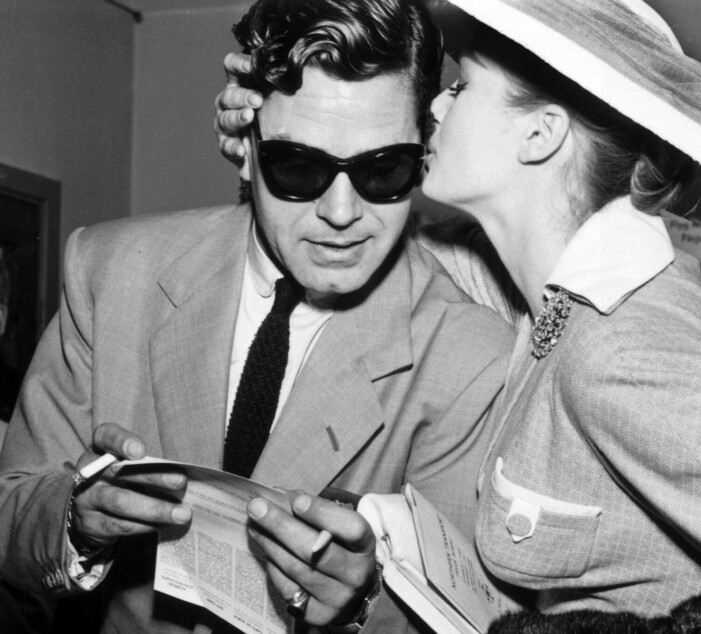 Anthony Steele i solglasögon får en puss av hustrun Anita Ekberg.
