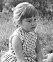En ung Ann Westin i prickig klänning på en äng. 