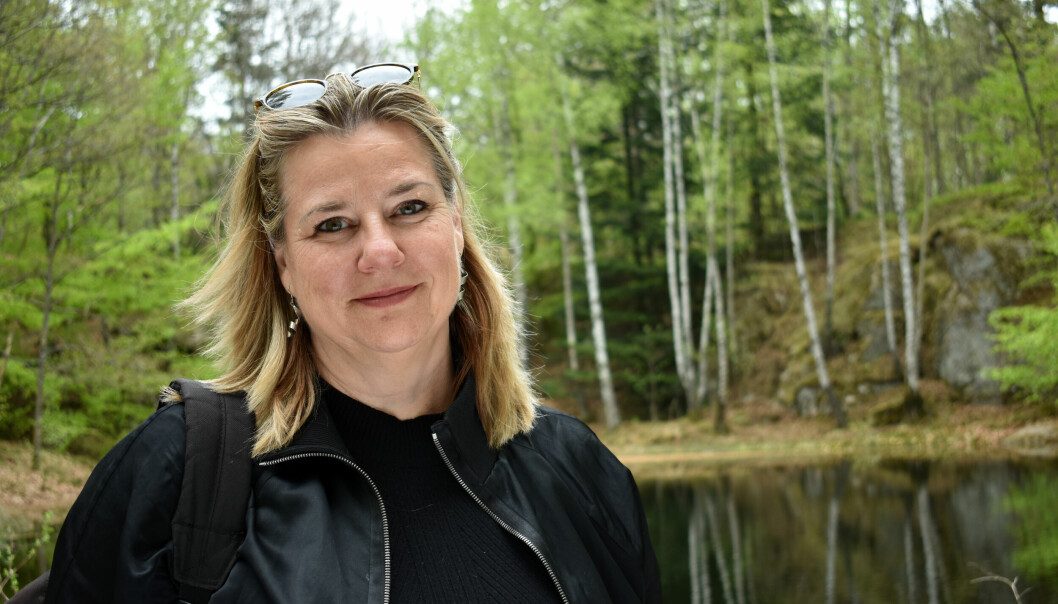 Anna Carlstedt fotograferad framför en liten sjö inne i en vårgrön skog.