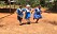 Tre barn springer hand i hand i en by i Uganda.