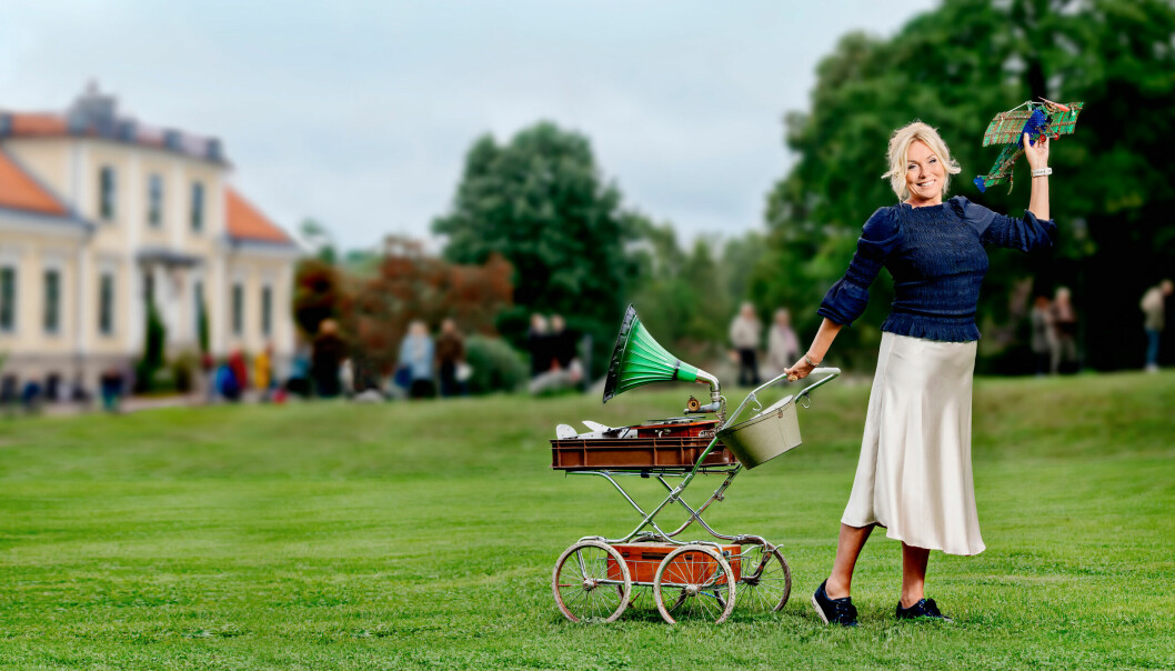 Anne Lundberg med en gammal barnvagn och andra antikviteter på en pressbild för Antikrundan 2022.