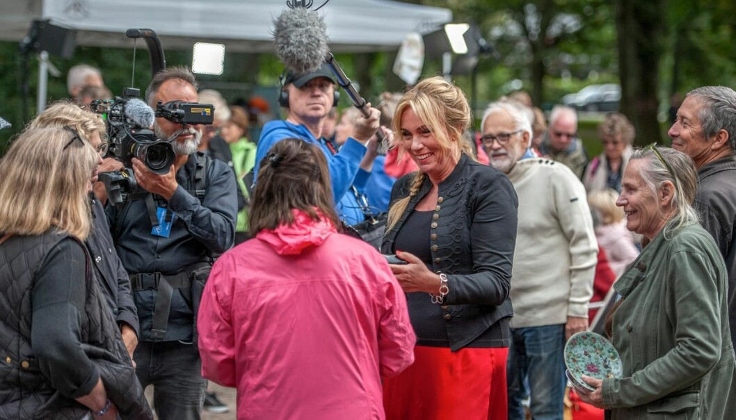 ”Får jag se?” Anne Lundberg går runt bland besökarna med ett av inspelningsteamen. Hon småpratar, ställer frågor och tittar på föremål de tagit med sig. Ett inslag som även uppskattas av de omkringstående. Foto: Erik Karlsson Anne Lundberg går runt bland besökarna på Antikrundan i Ronneby.