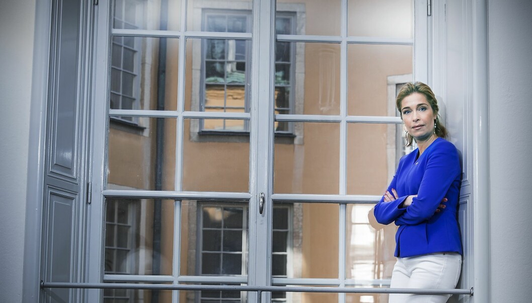 Annika i blå kofta står uppe i ett stort vitt fönster.