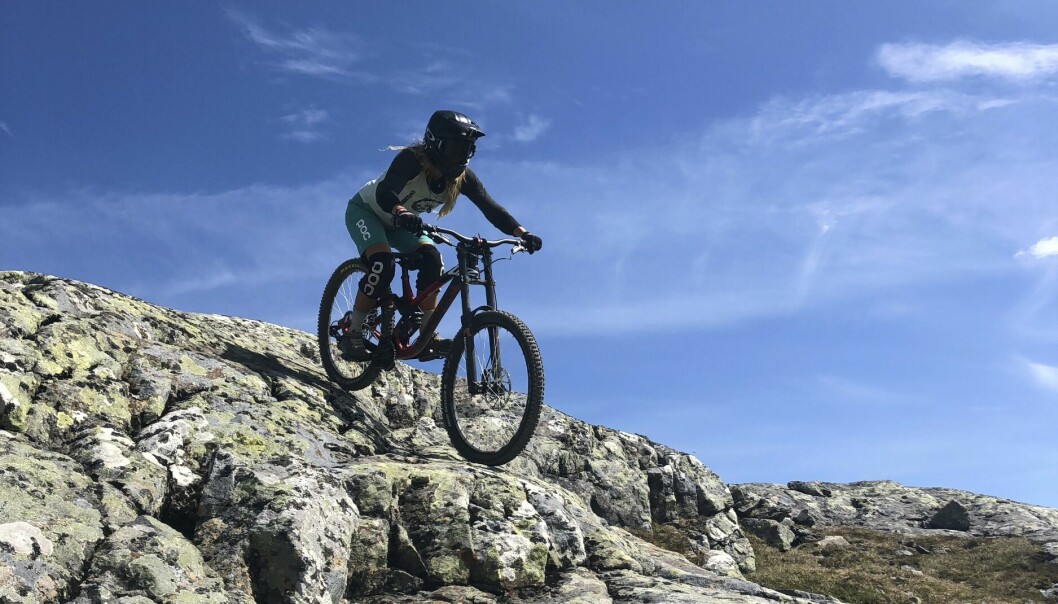 En ung kvinna cyklar mountainbike nerför ett berg.