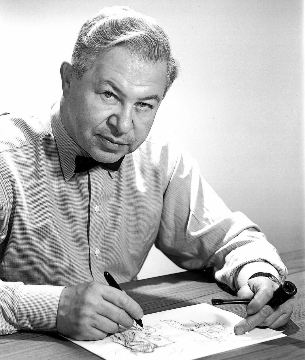 Arne Jacobsen, arkitekter och formgivare, skissar i ett block och tittar in i kameran