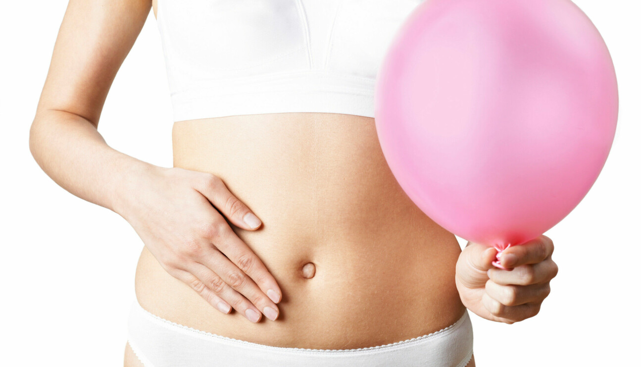 Kvinna håller en ballong i handen och visar sin mage, kanske har hon IBS?