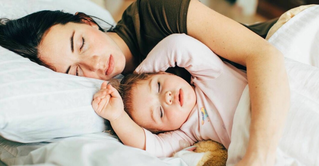 Kvinna och litet barn sover i sängen