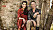 Bild på Sofia och Tareq, de sitter på några nedhuggna träd med en tegelvägg bakom. Sofia har en röd byxdress på sig.