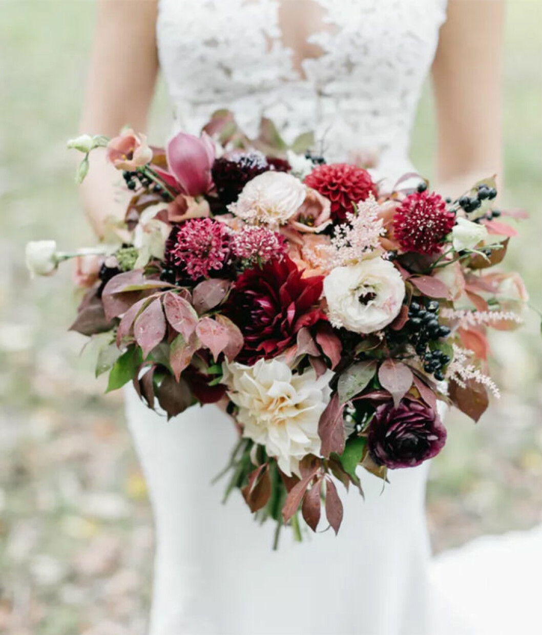Foto via: <a href="https://www.theknot.com/real-weddings/fall-bouquet-with-dahlias-berries-and-leaves-photo?context=wedding-bouquets-photos&page=2" target="_blank" rel="noopener">The Knot</a> Höstig brudbukett med mörkröda blommor