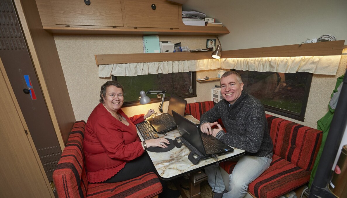 Husvagnen är både hem och arbetsplats för Carina och Thomas. Carina och Thomas sitter mittemot varandra vid den lilla matplatsen i husvagnen och har sina bärbara datorer framför sig.