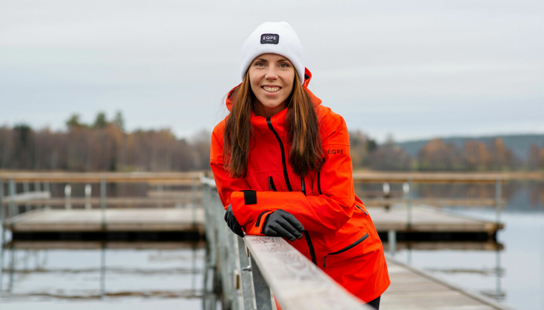 Charlotte Kalla står på en brygga. Hon har på sig en röd jacka och vit mössa.