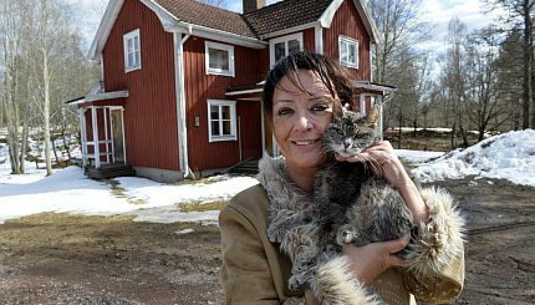 Ann-Christine Bärnsten håller sin katt utanför sitt hus.