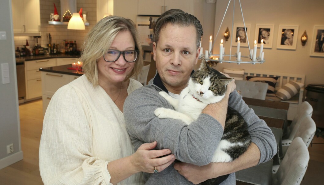 Fredrik och Susanne håller i sin katt Dexter i famnen. Susanne har en vit tröja och glasögon på sig.