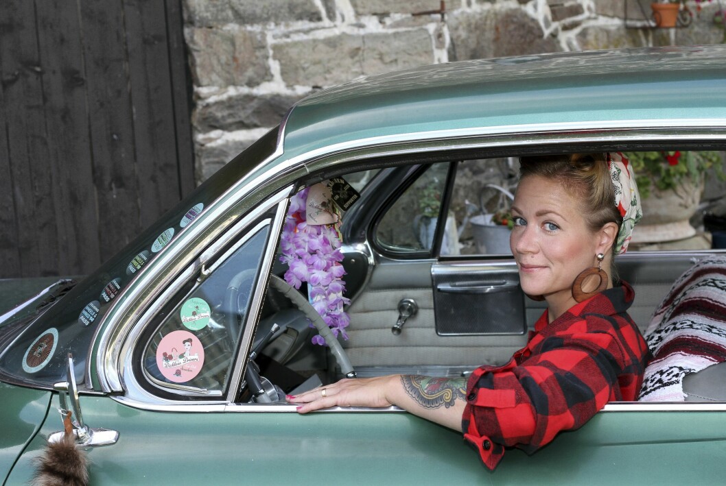 Julia Lind tittar ut genom sidorutan på sin gröna Cadillac coupé Deville. Inne i bilen skymtar lite retropynt.