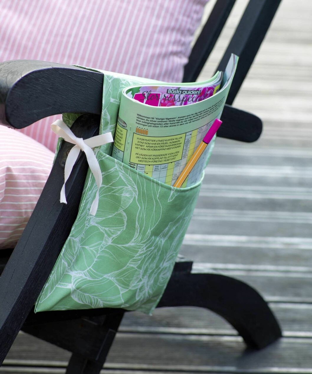Den snygga stolsfickan är perfekt förvaring för böcker, tidningar eller annat smått och gott som förgyller stunden i vilstolen. Stolsficka i grönt tyg med tidning i på trädgårdsstol