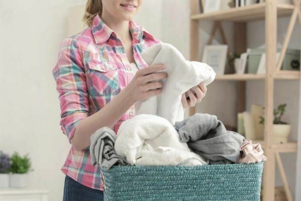 För den doftkänslige är det inte smutstvätten som är besvärande, utan ren tvätt med doft av sköljmedel. Young woman in pink/green/yellow shirt folding clean laundry.
