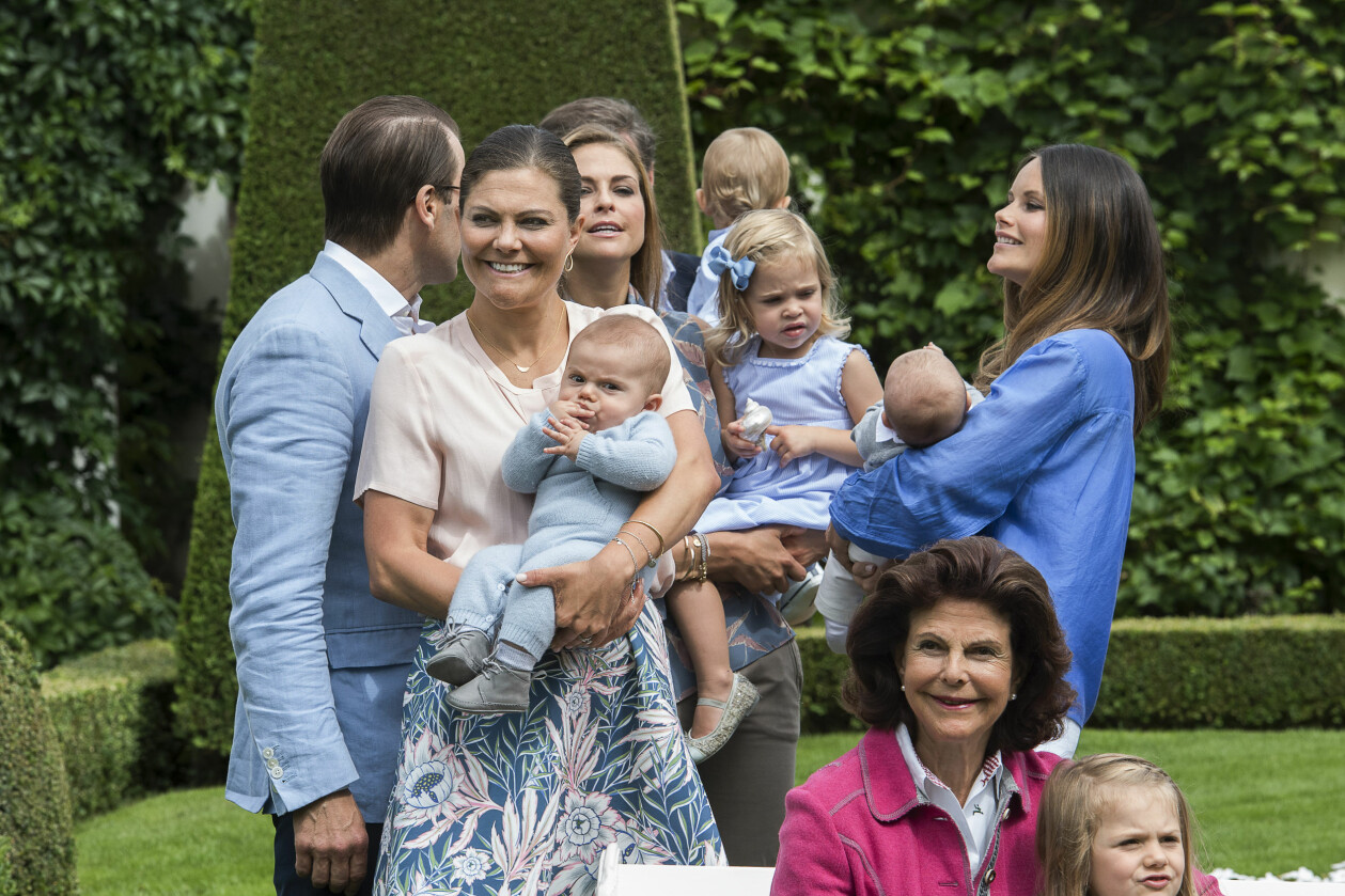 Att få med hela familjen på bild är inte alltid så enkelt. Så här såg det ut när släkten skulle fotografers på Öland för några år sedan. Längst ner till höger ser vi en lugn och trygg drottning Silvia med Estelle i famnen. Gruppfotografering av kungliga familjen på Sollidens slott 17 juli 2016. Från vänster prins Daniel, kronprinsessan Victoria med prins Oscar, prinsessan Madeleine med prinsessan Leonore, prinsessan Sofia med prins Alexander och sittanmde i soffan drottning Silvia med prinsessan Estelle.