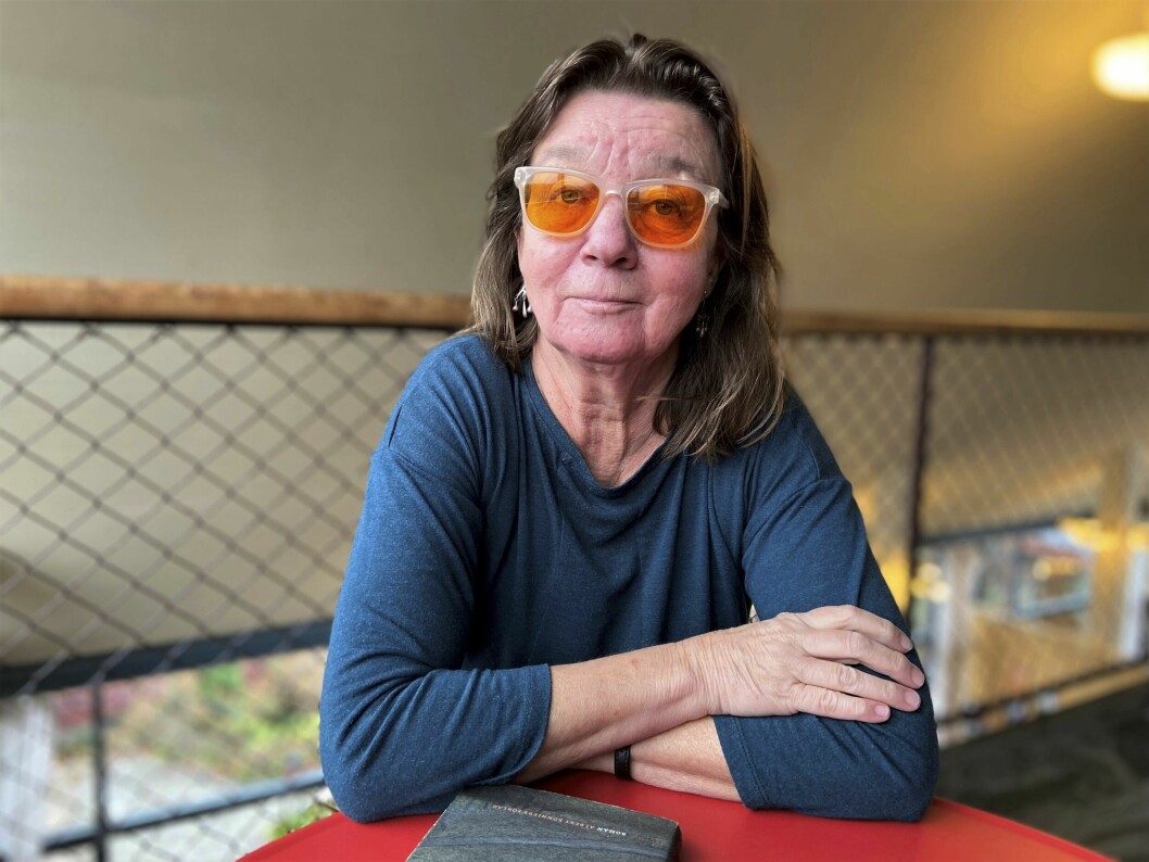 – Som författare kan jag använda mig av mig själv och min erfarenhet. Hur kan jag litterärt utnyttja det som hänt mig? funderar Elisabeth. Elisabeth bär brandgultonade glasögon och sitter med en bok framför sig.