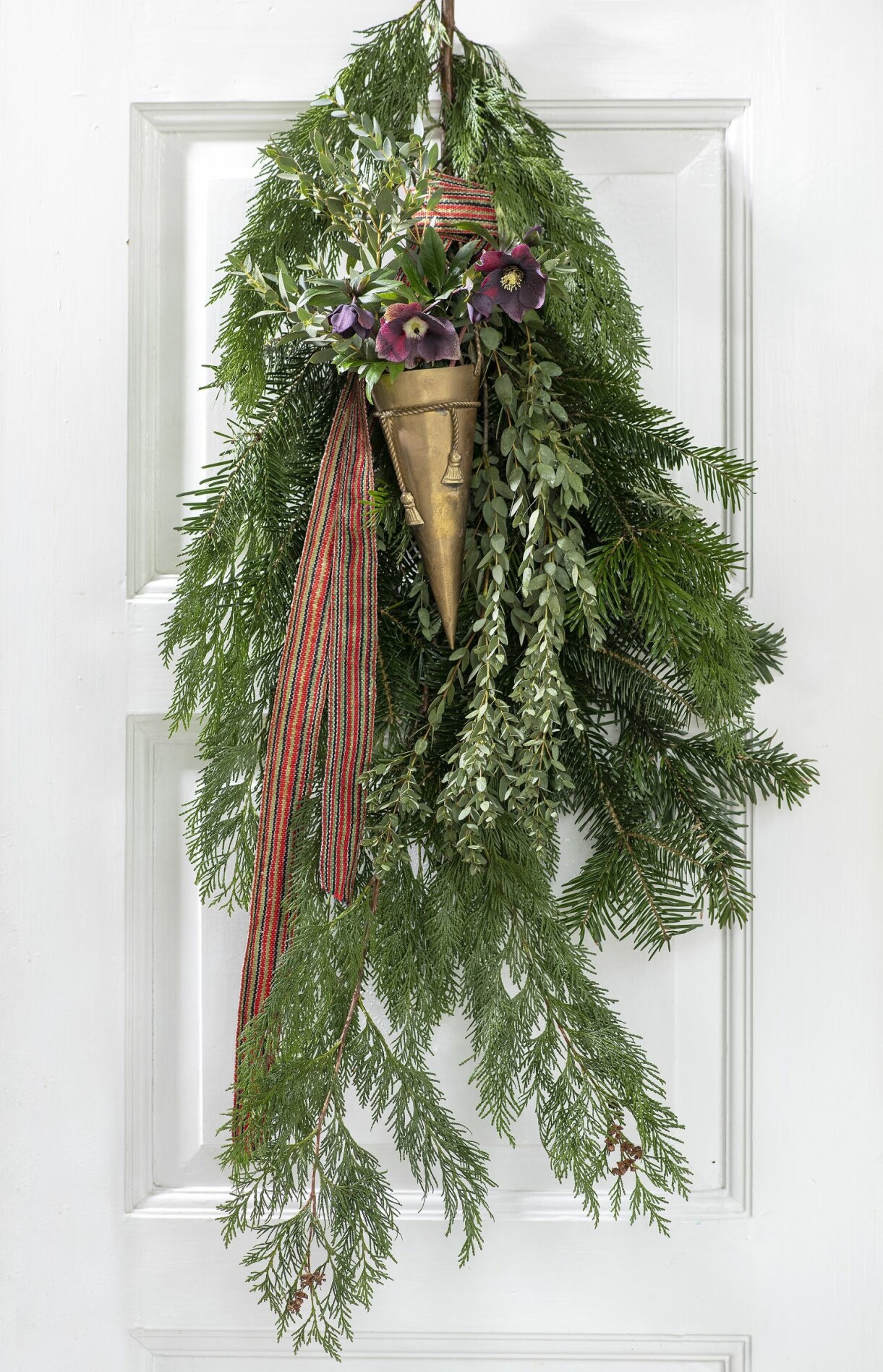 En dörrdekoration med cypress, eukalyptus och purpurfärgad julros kan sprejas med vatten, så är den fräsch länge. En enkel och snygg dörrdekoration till julen.
