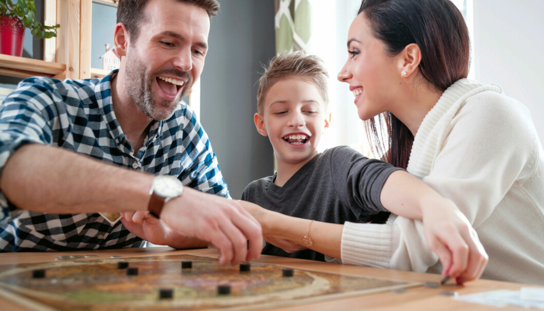 En familj sitter och spelar sällskapsspel