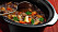 En köttgryta med morot och persilja i en slow cooker fotograferad uppifrån.