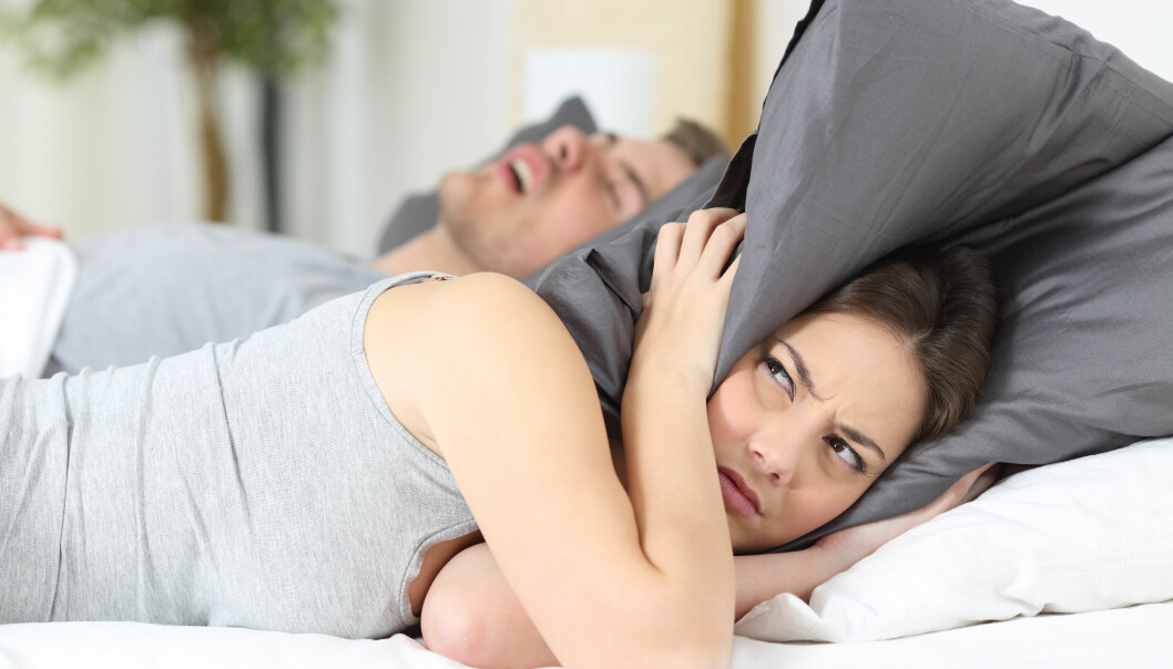 En kvinna försöker sova men mannen som snarkar tvingar henne att ha kudden över huvudet.