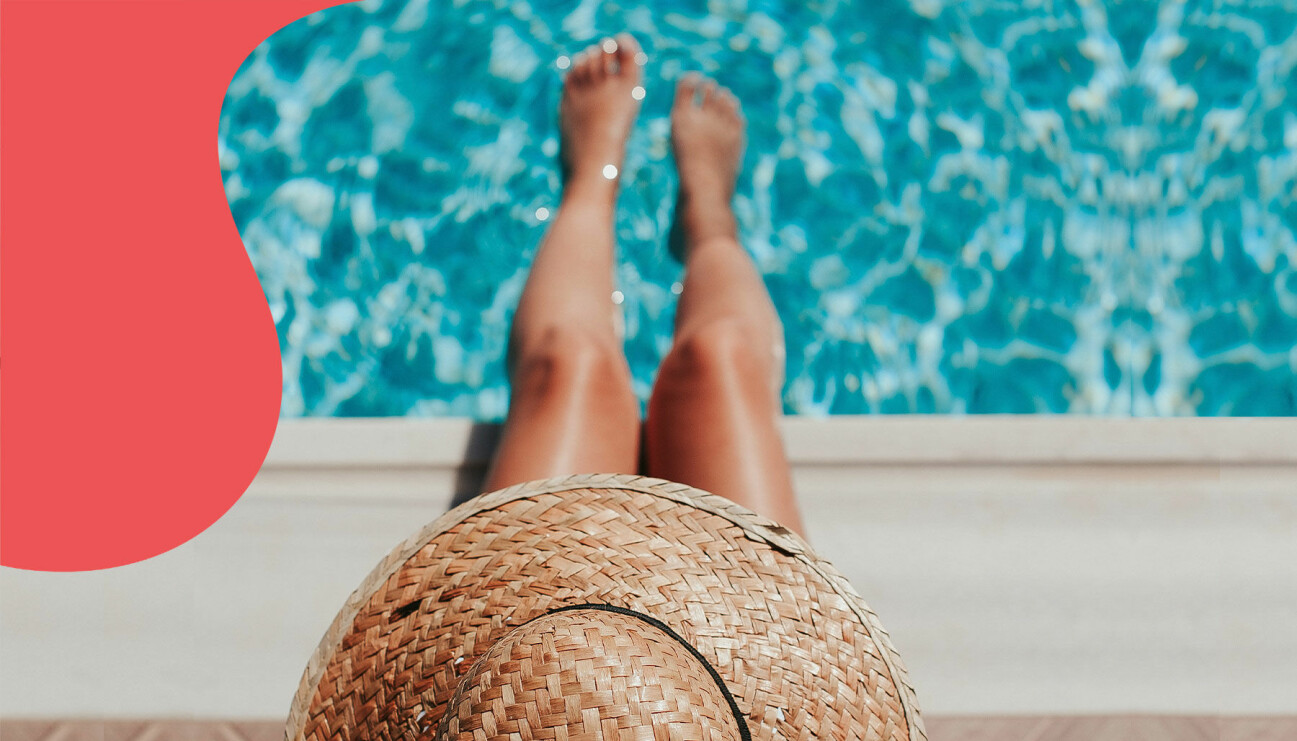 En kvinna i solhatt doppar fötterna i poolen.