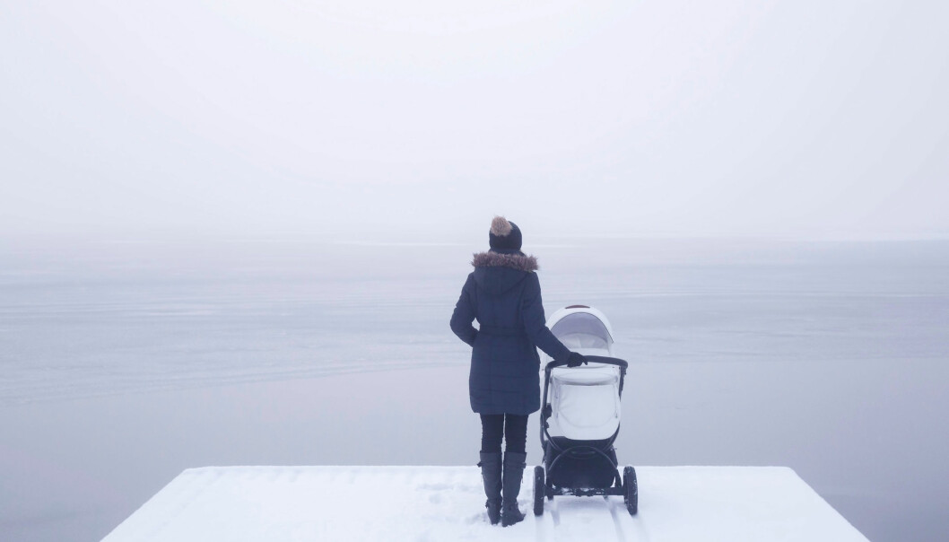 En kvinna med barnvagn står och tittar ut över havet i vintertid.