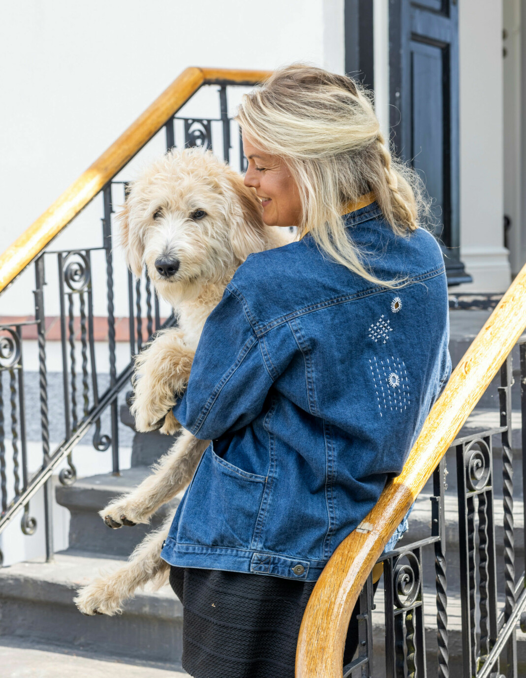 En kvinna står på en trappa med en hund i famnen