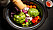 En slow cooker fylld med grönsaker som morot, rödlök, vitlök och kronärtskockor.