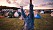 En ung tjej står med händerna i luften framför ett festivalområde fullt av tält.